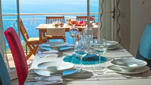 A table set for dining with a view of the sea, a balcony, and a dining area with chairs and a table. - Casa Mimì in Moressa area (Praiano)