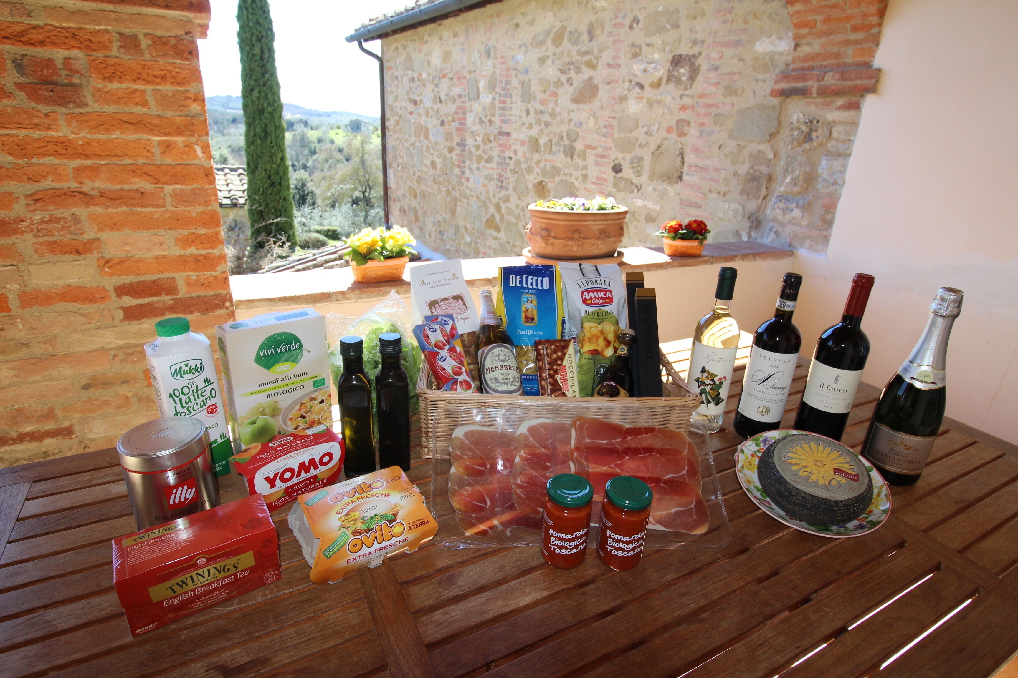 Une table garnie de divers aliments, de boissons et d’un panier de produits frais.