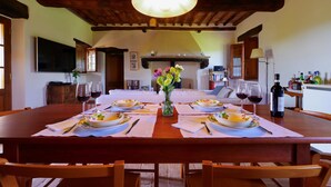 A dining area with a wooden table set for four, a vase of flowers, and wine glasses.