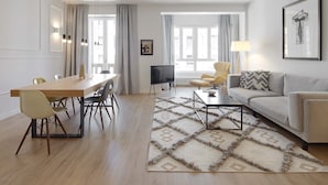 A modern living room with a wooden dining table, beige sofa, and a patterned rug.