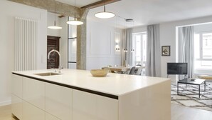 A modern kitchen with a large island, pendant lights, and a dining area with a TV and a rug.
