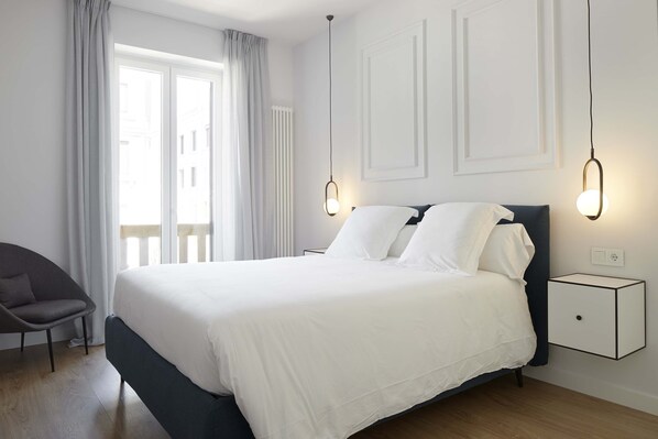 A modern bedroom with a large bed, a chair, and bedside lamps. - Wiesbaden by FeelFree Rentals (San Sebastián)