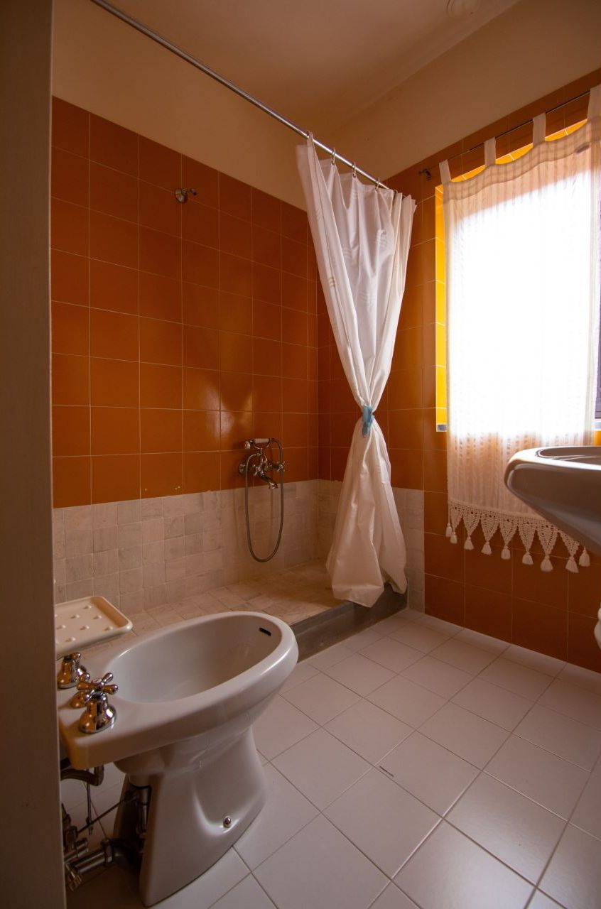 Un baño con bañera, bidé y ventana con cortinas.