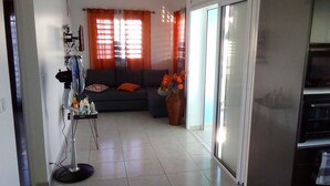 A living room with a sofa, a vase with flowers, and a fan.