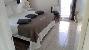 A hotel room with a bed, pillows, a chair, and a small table.