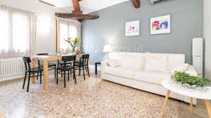 Una sala moderna con comedor, muebles blancos y suelo moteado.