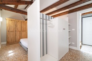 A bedroom with a bed, wooden wardrobe, and a white wardrobe with shelves.