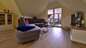 Un salón amplio con un sofá gris, una mesita de centro y un televisor sobre un mueble.