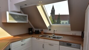 Una cocina moderna con tragaluz, lavavajillas y vistas a una torre de iglesia.