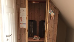 Un cuarto pequeño de madera, con puerta, un cartel y una toalla en un estante.