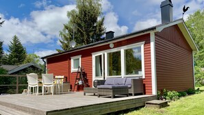 A red cabin with a deck, two wicker sofas, and a table with chairs. - Idyllic holiday home near Örkelljunga, sun terrace, wood-burning stove, forests and lakes (Örkelljunga)