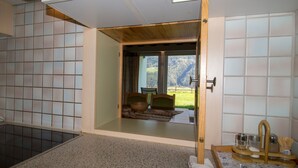 A room with a large sliding glass door leading to a balcony with a view of a green landscape. - Chalets St. Wendelin (Telfs)