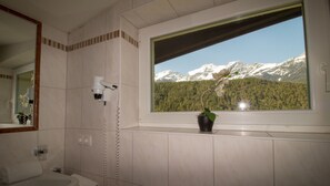 A bathroom with a window view of snow-capped mountains and a potted orchid. - Chalets St. Wendelin (Telfs)