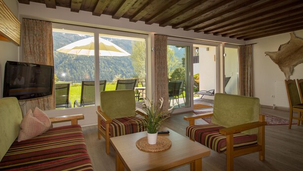 A modern living room with a sofa, chairs, a coffee table, and a TV. - Chalets St. Wendelin (Telfs)