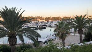 A marina with boats docked, surrounded by palm trees and buildings in the background. - House for 8 people (4 bedrooms) with swimming pool and superb view of the marina (Cala d'Or)