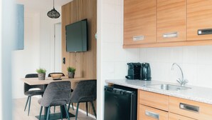 Una cuina moderna amb armaris de fusta, un rentaplats negre, una cafetera i una zona de dinar amb taula i cadires.