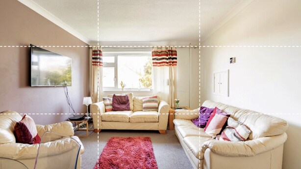 A living room with two white sofas, a red rug, and a window with curtains.