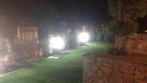 A nighttime view of a well-maintained garden with a stone wall and a wooden fence. - Palau (OT), 650 meters from the beach, ideal for couples and families (PALAU (OT))