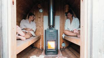 A sauna with two wooden benches and a central wood-burning stove.