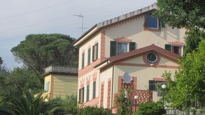 Ein zweistöckiges Gebäude mit Balkon, umgeben von üppiger Vegetation.