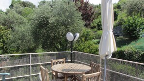 Ein Holztisch und Stühle auf einer Terrasse mit Blick auf Grünflächen.