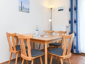 Ein Essbereich mit Holztisch und -stühlen, einer Stehlampe und einem Heizkörper.