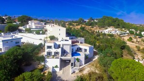 A modern white building with a blue swimming pool, surrounded by greenery and other residential structures. - Amazing 2 bed villa, private pool, close to beach/restaurants/bars/golf/tennis (Carvoeiro)