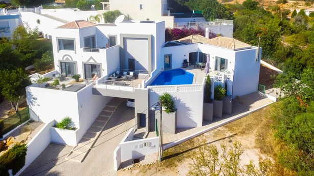 A modern white villa with a swimming pool, multiple balconies, and a view of the surrounding landscape. - Amazing 2 bed villa, private pool, close to beach/restaurants/bars/golf/tennis (Carvoeiro)