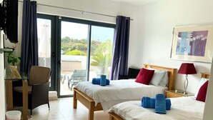 A hotel room with two beds, a desk, a chair, and a view of the outdoors. - Amazing 2 bed villa, private pool, close to beach/restaurants/bars/golf/tennis (Carvoeiro)