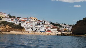A coastal town with buildings along the cliffside, a beach with people, and a clear sky. - Amazing 2 bed villa, private pool, close to beach/restaurants/bars/golf/tennis (Carvoeiro)