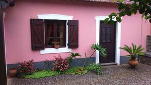 A building with pink walls, a cobblestone courtyard, and a door with a window. - Rural Tourism - Laurissilva Forest (Camacha)