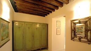 Un pasillo con un armario verde, obras de arte enmarcadas en las paredes y un techo de madera.