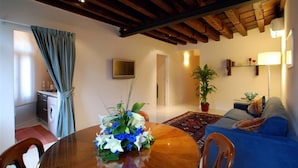 Una sala de estar con una mesa de comedor de madera, un sofá azul y una planta en maceta.