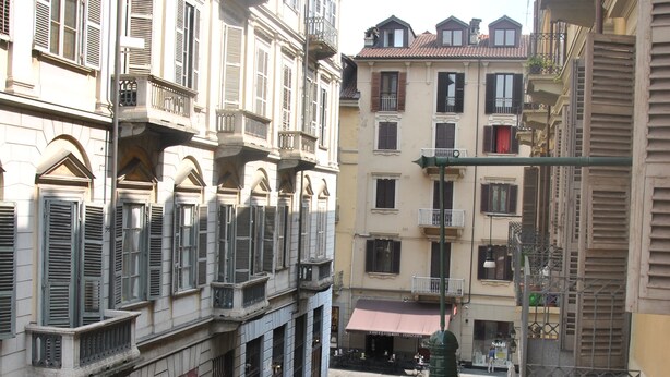 A courtyard with outdoor seating and a fountain, surrounded by multi-story buildings with balconies and shutters. - Casa Rattazzi, elegant apartment in the heart of the city (torino)