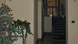 A hallway with a large potted plant, a staircase, and a wall-mounted light fixture. - Casa Rattazzi, elegant apartment in the heart of the city (torino)