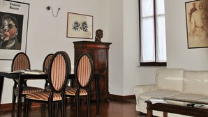 A room with a wooden floor, a white sofa, a dining table with chairs, and a ceiling with intricate designs. - Casa Rattazzi, elegant apartment in the heart of the city (torino)