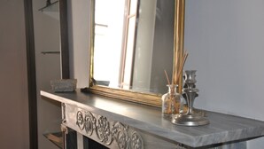 A marble fireplace with a large mirror above it, a small vase with reed sticks, and a candle holder. - Casa Rattazzi, elegant apartment in the heart of the city (torino)