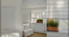 Een kamer met een bed, een radiator en een raam met zonwering.