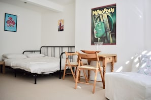 A bedroom with a bed, a desk, a chair, and a poster on the wall.
