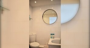 Et badeværelse med toilet, håndvask og spejl.