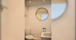 A bathroom with a toilet, a sink, and a mirror.