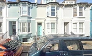 A row of terraced houses with bay windows and a car parked in front.