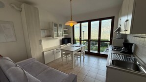 Una cucina compatta con zona pranzo, un divano e vista attraverso ampie finestre.