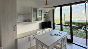 Una cucina moderna con zona pranzo, TV e vista su un paesaggio montuoso attraverso ampie finestre.