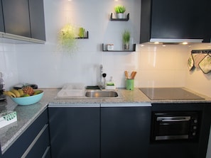 Enjoy cooking in this kitchen with a stainless steel sink, oven, and countertop with a dish rack.