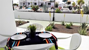 A dining table set with plates, wine glasses, and a potted plant.