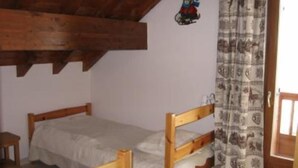Une petite pièce rustique avec un lit superposé en bois, une petite table de chevet et un rideau à motifs.