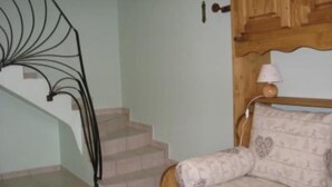 Un escalier avec une rampe en métal, une porte en bois avec un trou de serrure et un lit avec une literie à motifs.