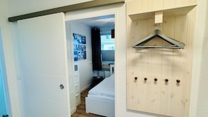 Ein Schlafzimmer mit Holzboden, einem Bett, einem Kleiderschrank und einer an der Wand befestigten Holzvertäfelung mit Haken.