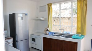 A compact kitchen with a refrigerator, oven, sink, and wooden cabinets. - Flic En Flac: Cosy Apartment in a nice setting (Flic en Flac)